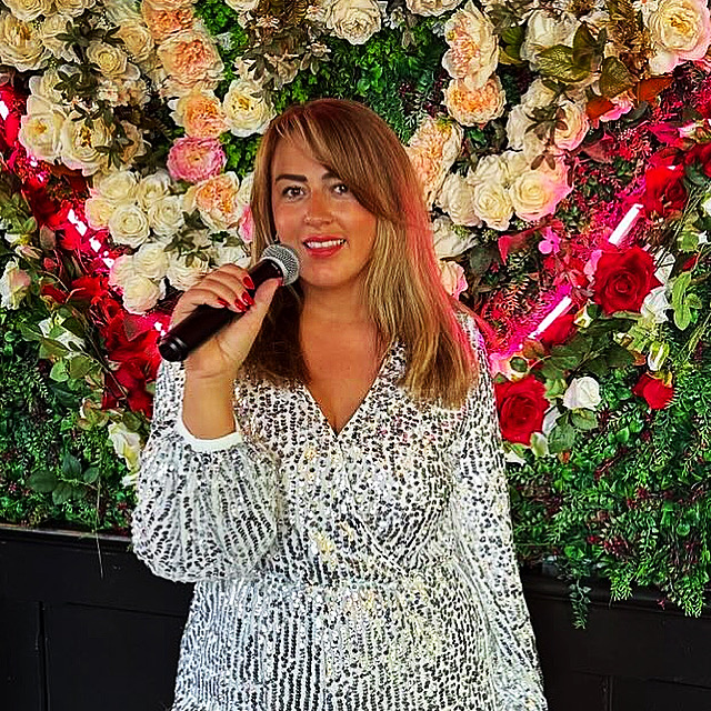 Emma Bennett singing in front of a flower wall